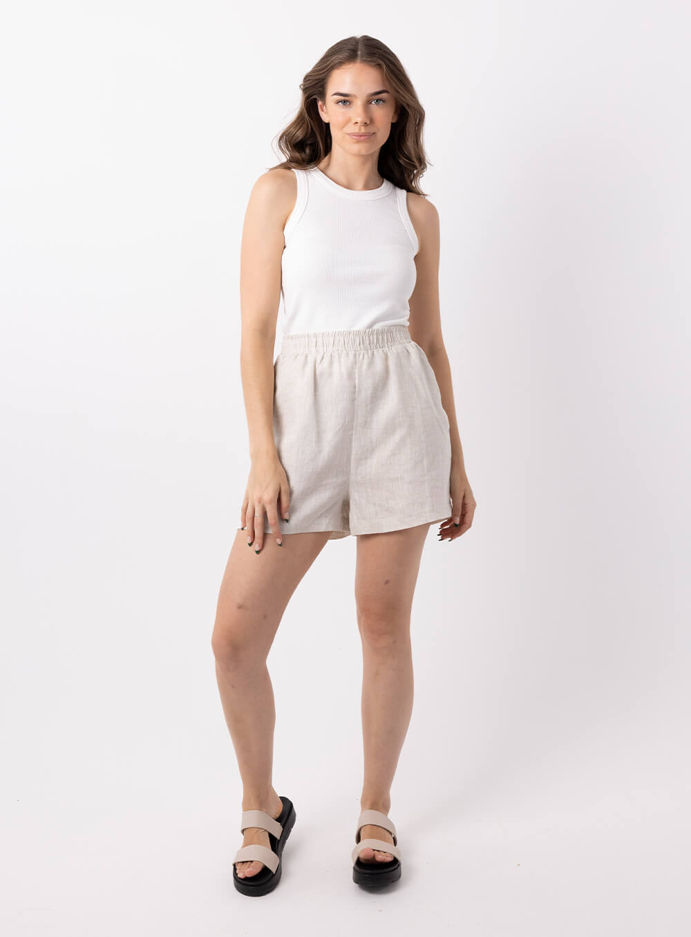 The Ali Linen Short in biege is 100% breathable lien, mid thigh in length with 2 side pockets, no back pockets, elastic waistband and designed to be worn high wiasted and loose fitting