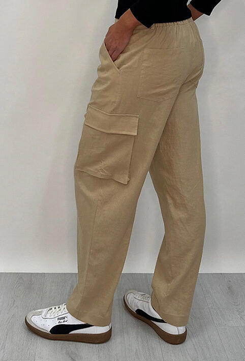 Athena Linen Cargo Pant in beige is 100% Linen, elastic waistband at back, belt loops, slightly tapered towards the hem, 2 Pockets at back, 2 Pockets on side leg
