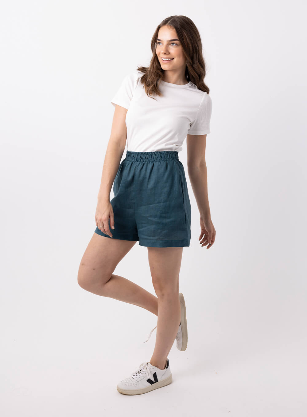 The Ali Linen Short in teal is 100% breathable lien, mid thigh in length with 2 side pockets, no back pockets, elastic waistband and designed to be worn high wiasted and loose fitting