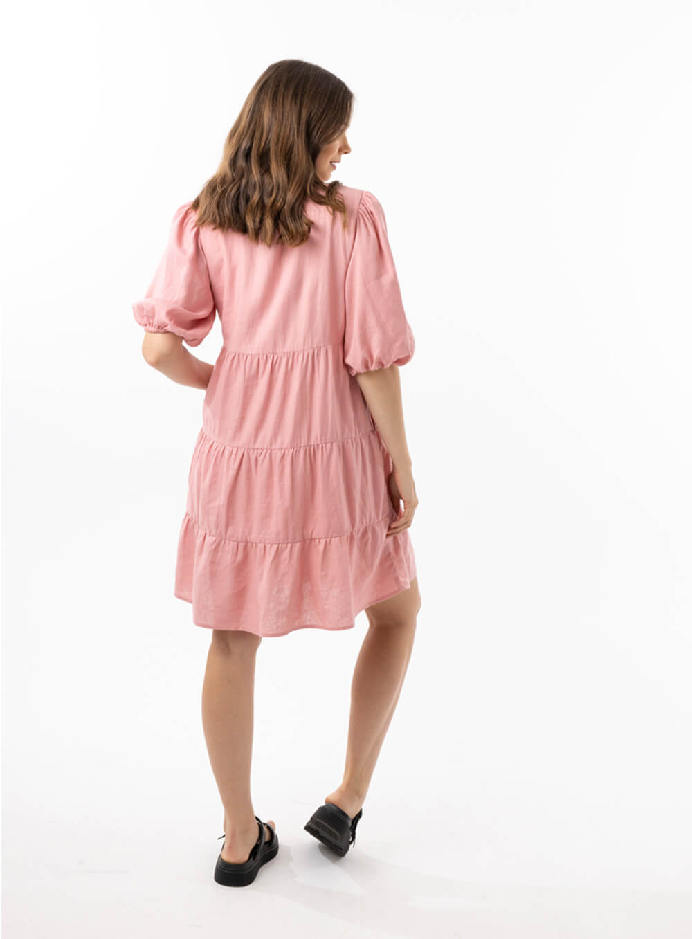 The Eleanor mini dress in blush pink features a flowing layered a line shape with draping linen/viscose fabric, puff 3/4 sleeves with elastic cuff which can be pushed up to the elbow, a dropped v shape neckline with a square finish.