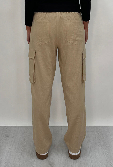 Athena Linen Cargo Pant in beige is 100% Linen, elastic waistband at back, belt loops, slightly tapered towards the hem, 2 Pockets at back, 2 Pockets on side leg