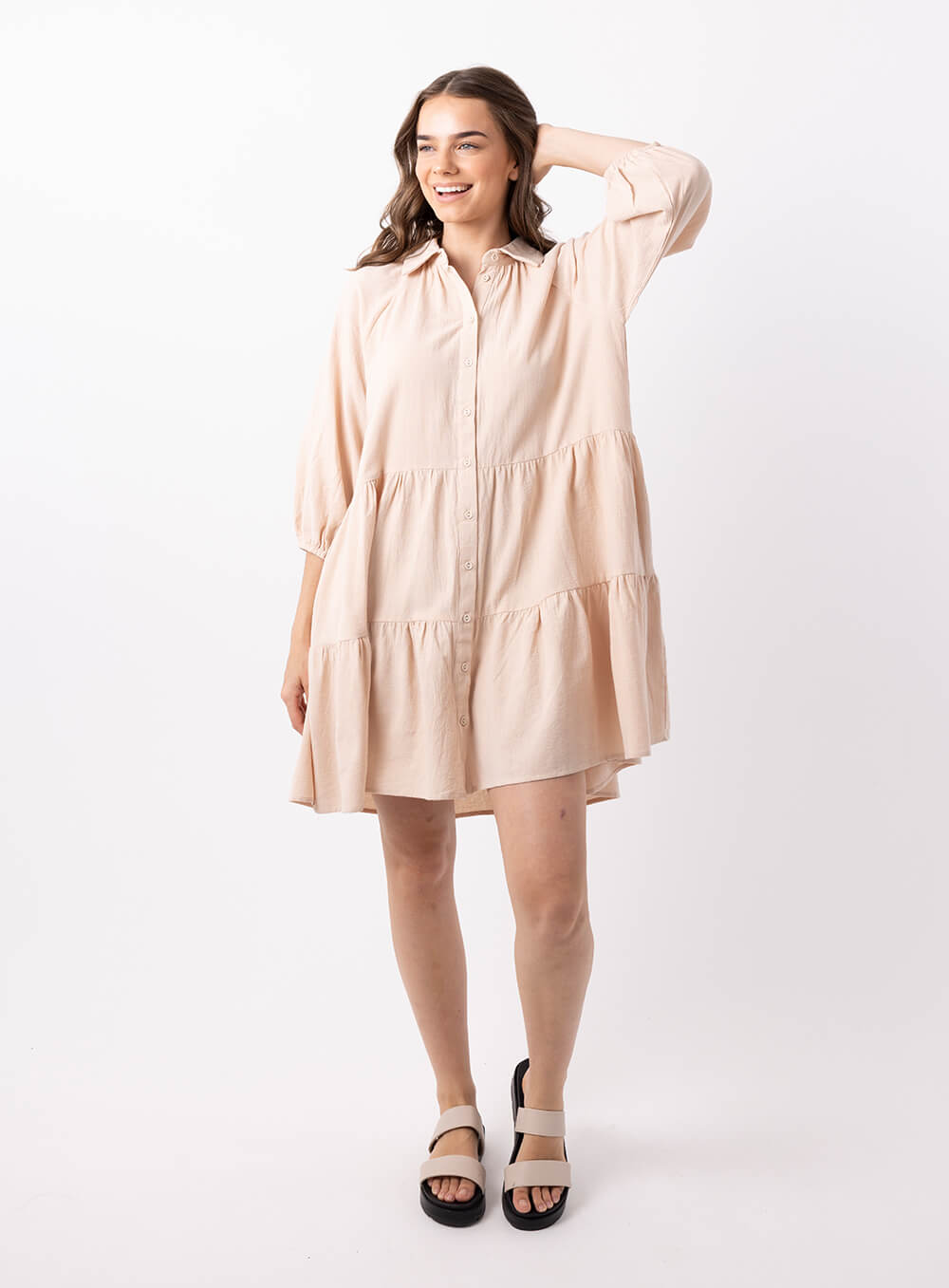 The Jasmine Dress in beige is made of 100% soft cotton, featuring a collar neck, 3/4 sleeve with elastic cuff button through front all the way to the hem, tiered layers through the body, midi in length and 2 side pockets