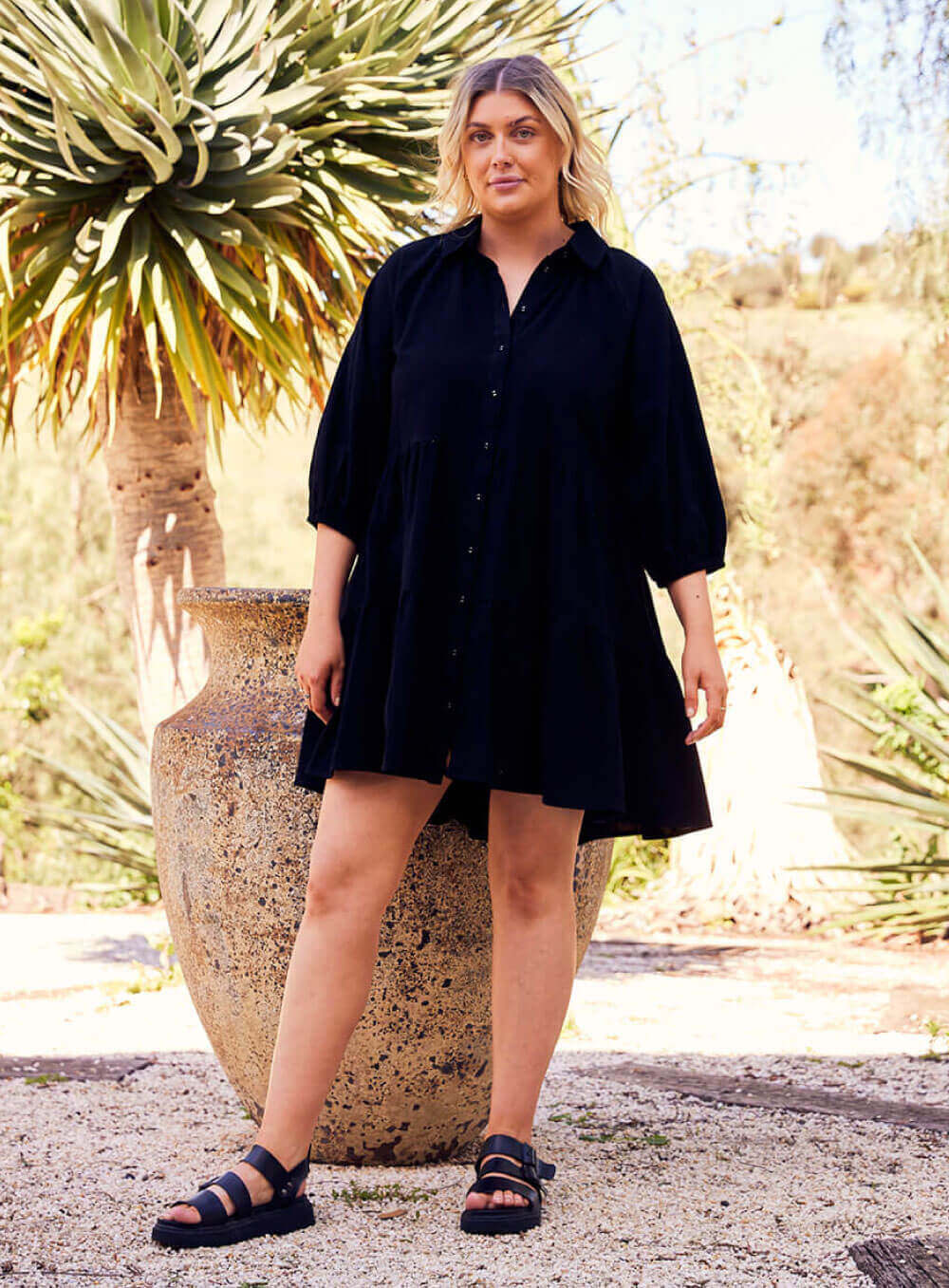 The Jasmine Dress in black is made of 100% soft cotton, featuring a collar neck, 3/4 sleeve with elastic cuff button through front all the way to the hem, tiered layers through the body, midi in length and 2 side pockets